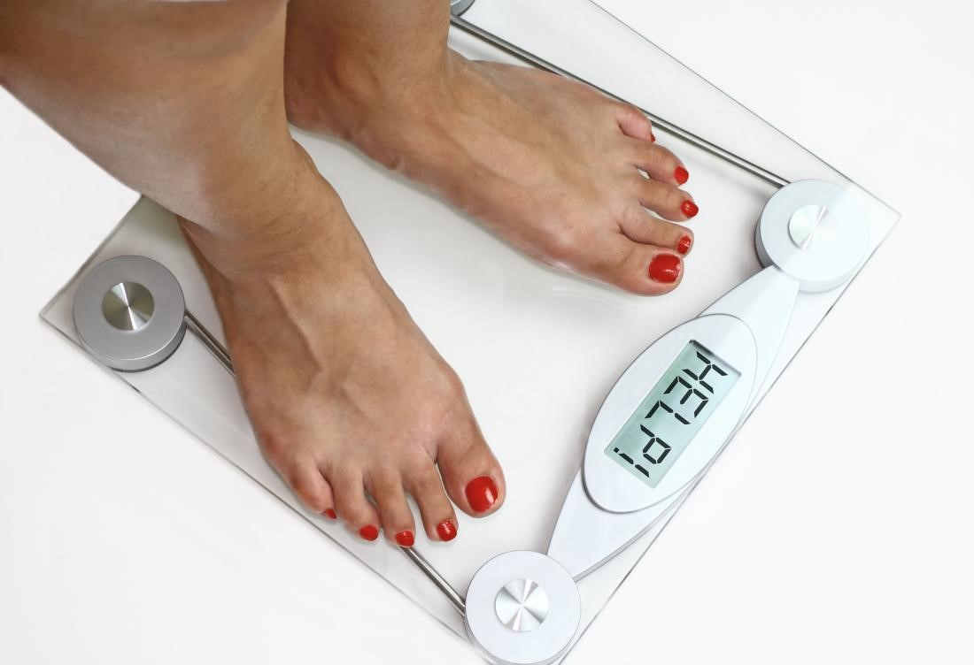 A woman 's feet standing on a scale with the weight displayed.