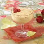 A glass of fruit and cream on a red plate.