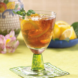 A glass of tea with lemon and mint on the side.