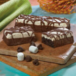 A wooden cutting board topped with brownies and marshmallows.