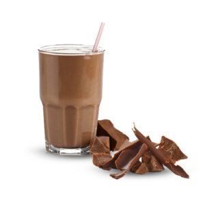 A glass of chocolate milk next to some pieces of chocolate.
