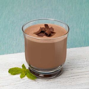 A glass of chocolate milk with a piece of chocolate on top.