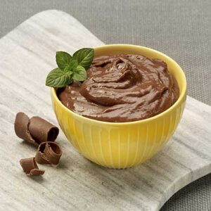 A yellow bowl of chocolate pudding on top of a wooden board.