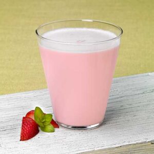 A glass of milk with strawberries on the side.