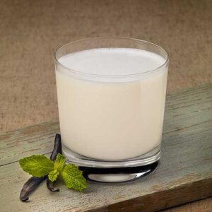 A glass of milk sitting on top of a wooden table.