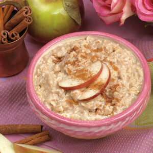 A bowl of oatmeal with apples and cinnamon sticks.