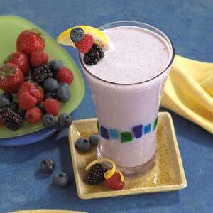 A glass of milk with fruit on the side.